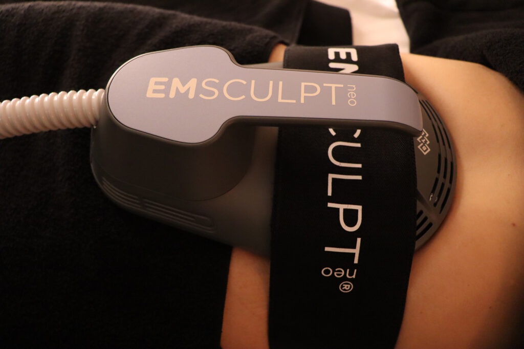 The Emsculpt NEO treatment band, attached to a patient's midsection with an elastic strap. This patient is currently receiving a body contouring near Brownsboro treatment targeted at the abs.