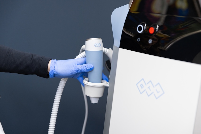 A provider prepares the Exion machine for a skin tightening treatment in Louisville. Wearing surgical gloves, the provider grabs the hand-held device that is used to administer the treatment.